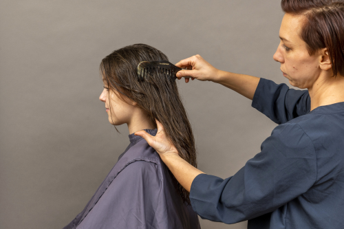 einem Mädchen mit langen braunen Haaren werden die Haare gekämmt